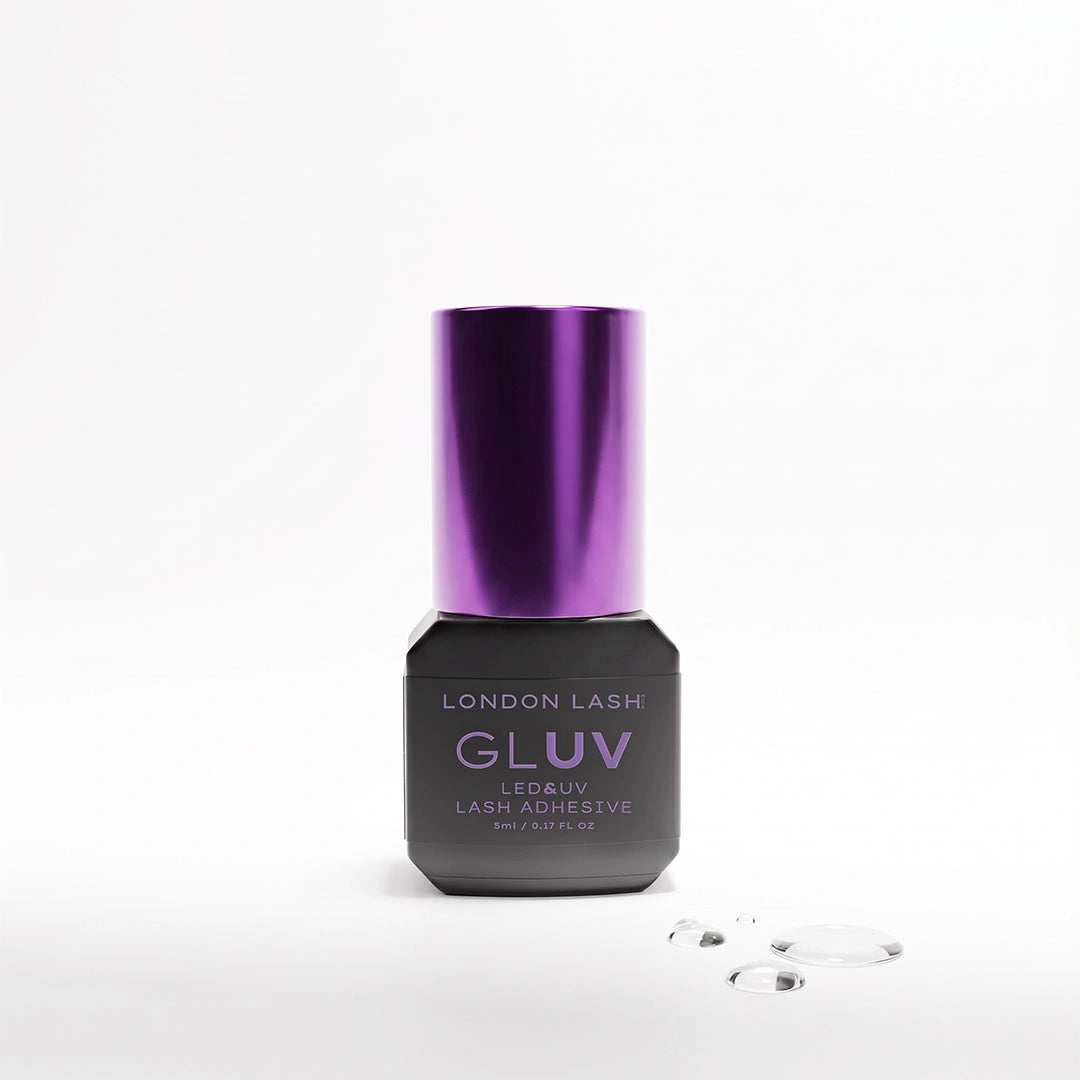 Flacon de 5 ml de la colle pour extensions de cils London Lash GLUV LED & UV avec un bouchon métallique violet, accompagné de gouttes de colle transparente sur un fond blanc.
